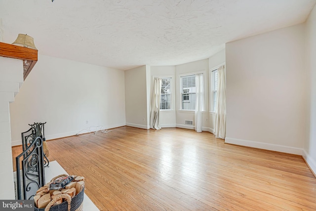 unfurnished living room with a textured ceiling and light hardwood / wood-style floors