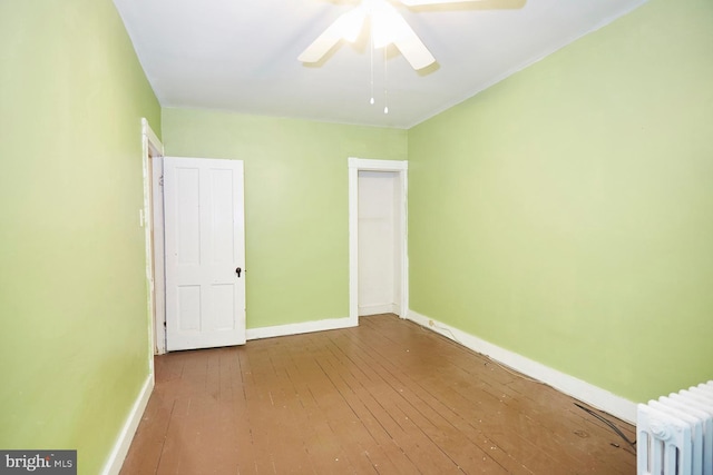 unfurnished bedroom with ceiling fan, radiator heating unit, and light wood-type flooring