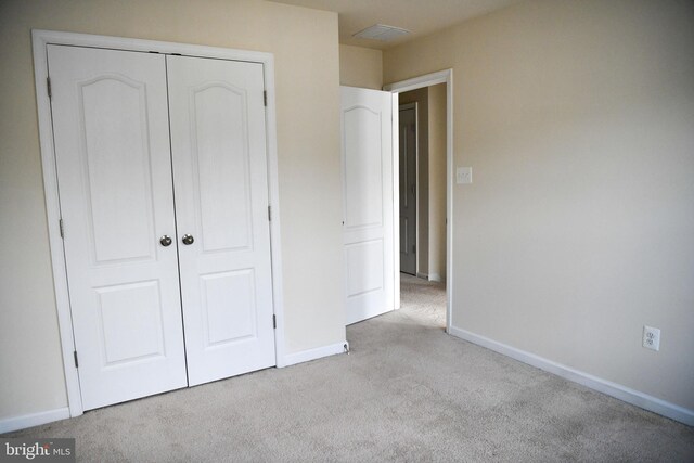 unfurnished bedroom with light carpet and a closet