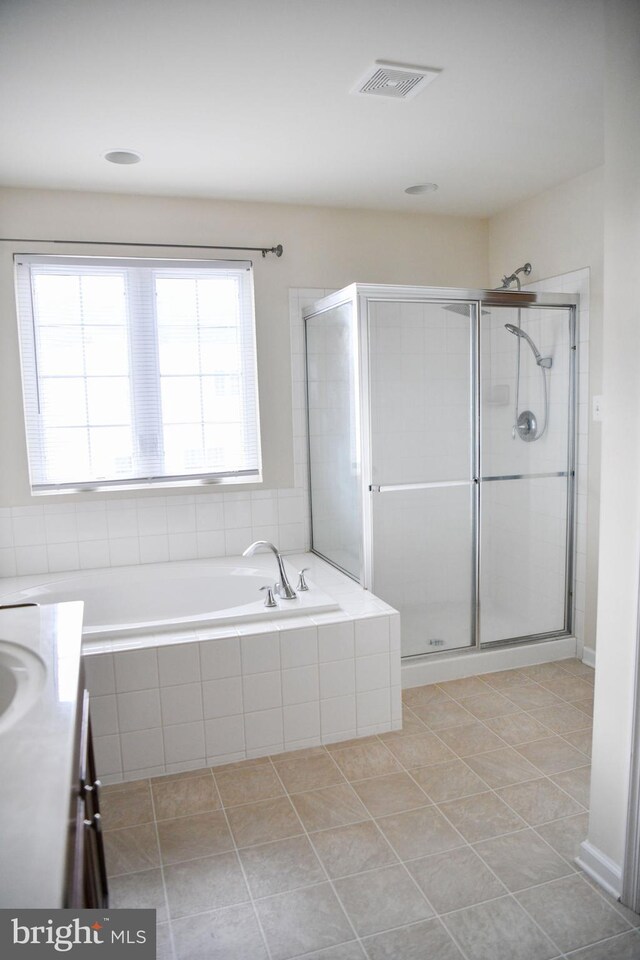 bathroom with tile patterned flooring, a healthy amount of sunlight, and shower with separate bathtub