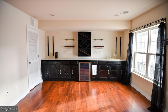 bar with a healthy amount of sunlight, wood-type flooring, sink, and wine cooler