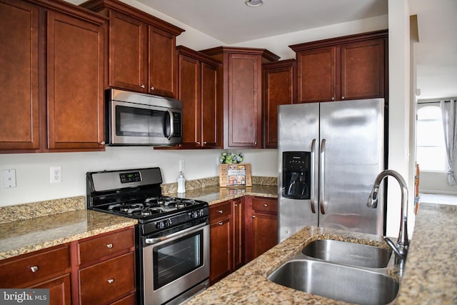 kitchen with stainless steel appliances, light stone counters, and sink