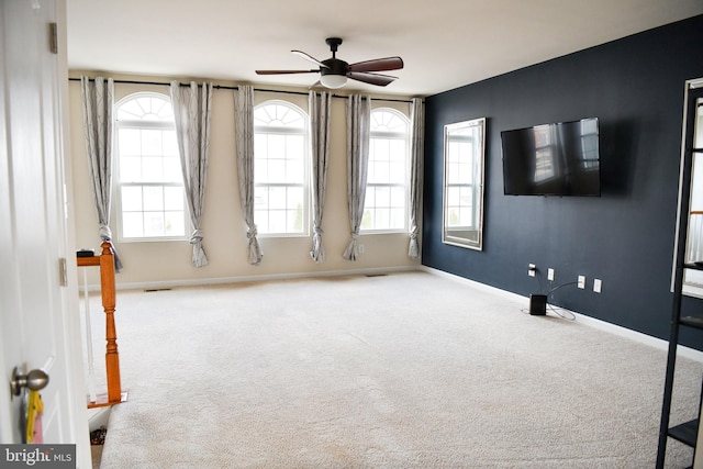 carpeted spare room with ceiling fan and plenty of natural light