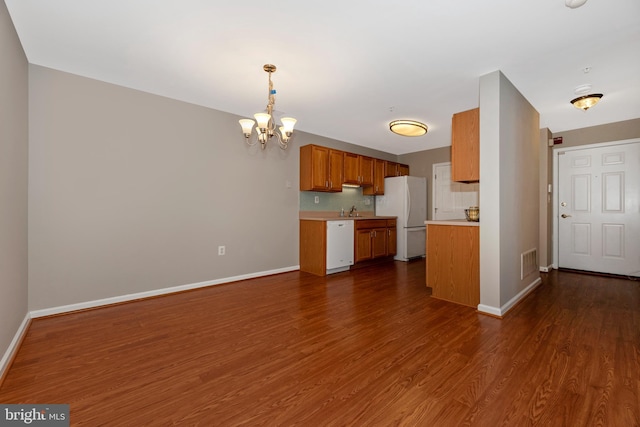 kitchen featuring an inviting chandelier, dark hardwood / wood-style flooring, backsplash, pendant lighting, and white appliances