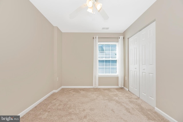 unfurnished bedroom with a closet, light colored carpet, and ceiling fan