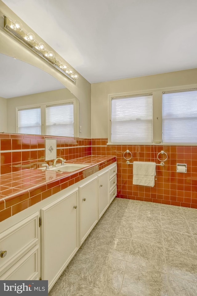 bathroom with vanity, tile walls, and a healthy amount of sunlight