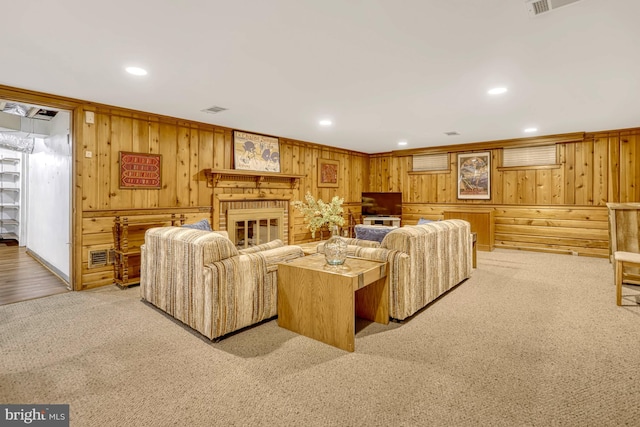 carpeted living room featuring a brick fireplace, wood walls, and ornamental molding