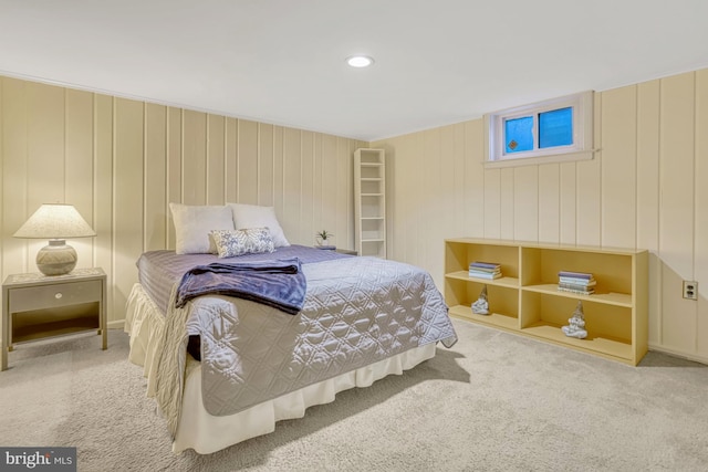 bedroom with light colored carpet and wood walls