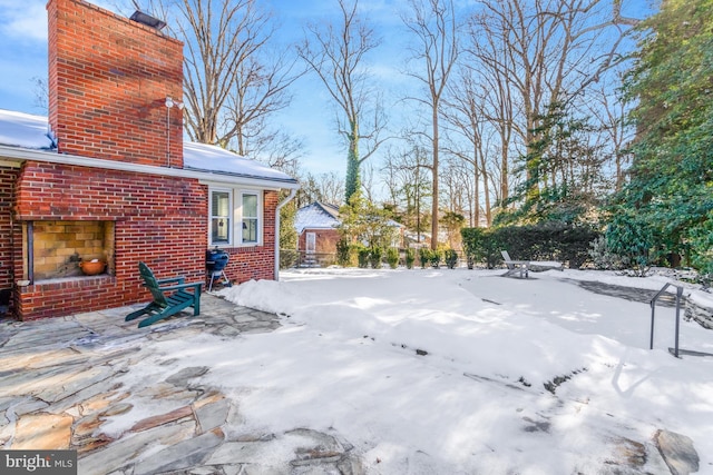 yard layered in snow featuring an outdoor brick fireplace