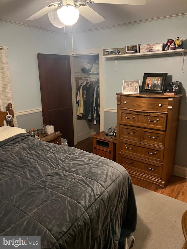 bedroom with hardwood / wood-style flooring, a closet, crown molding, and ceiling fan