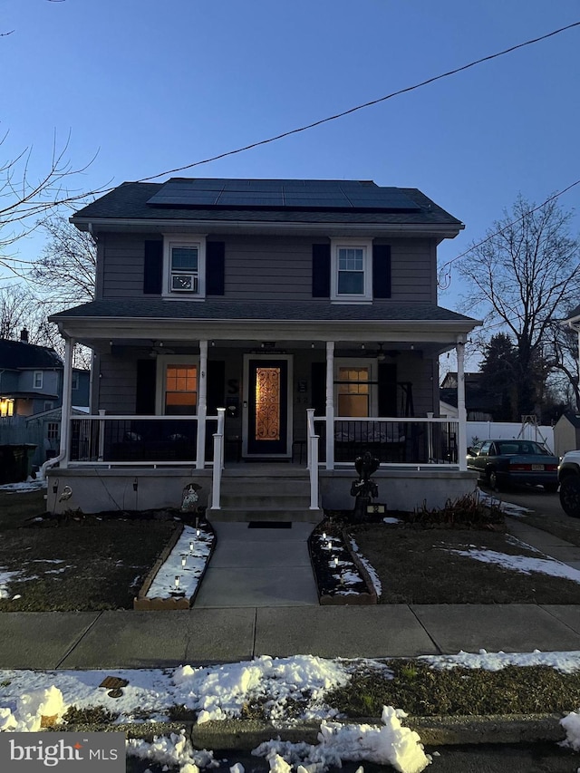 view of front of home featuring covered porch and solar panels