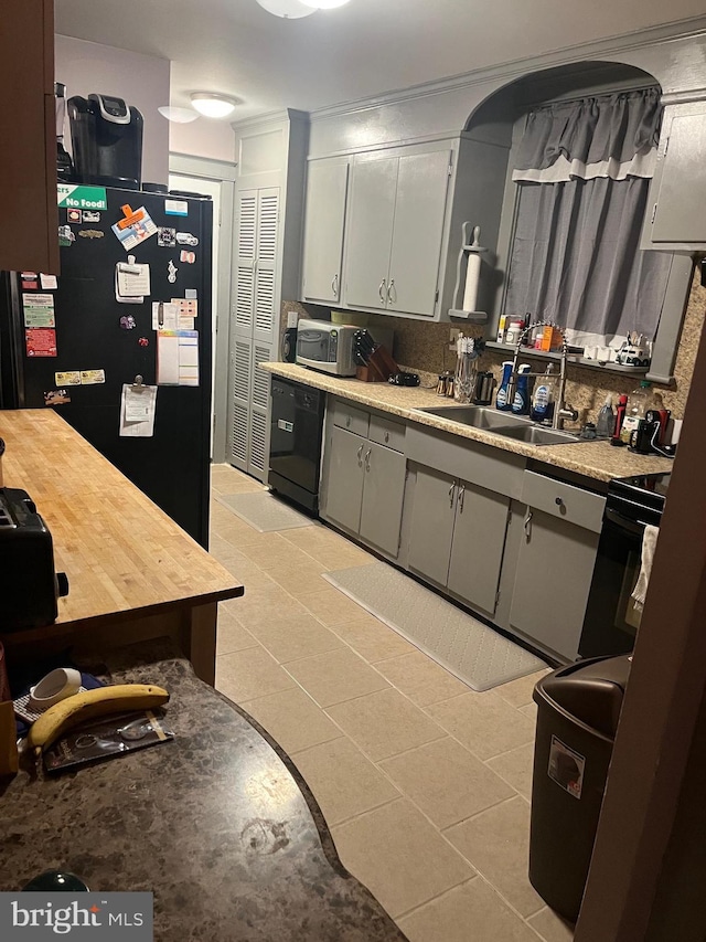 kitchen with sink, black dishwasher, backsplash, refrigerator, and light tile patterned floors