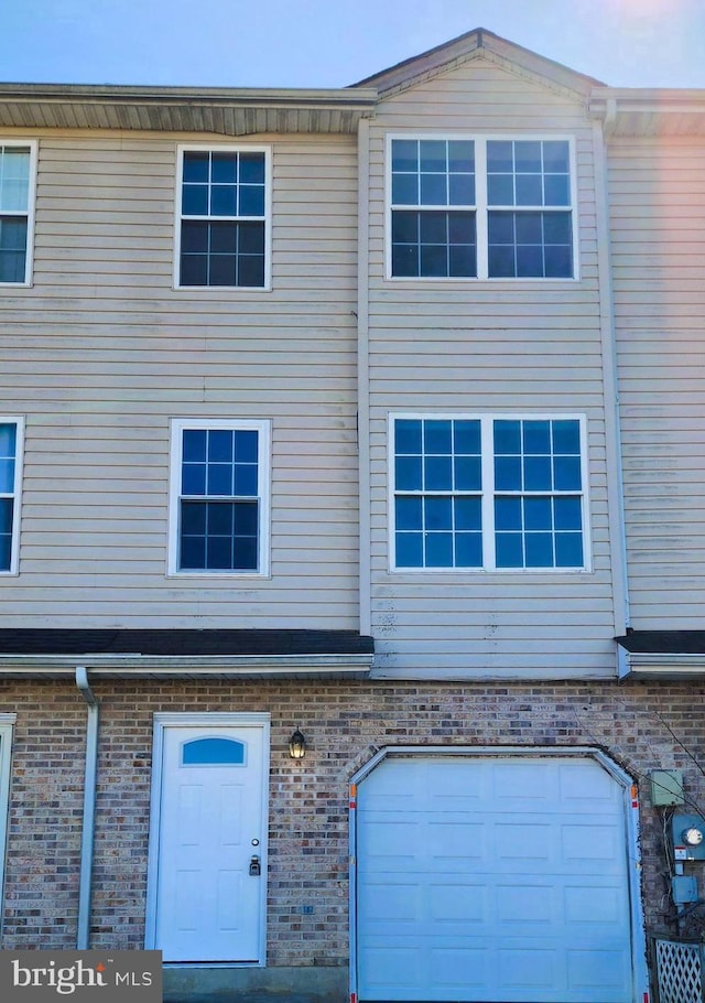 townhome / multi-family property with an attached garage and brick siding