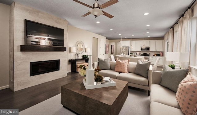 living room with dark hardwood / wood-style floors, a large fireplace, a textured ceiling, and ceiling fan