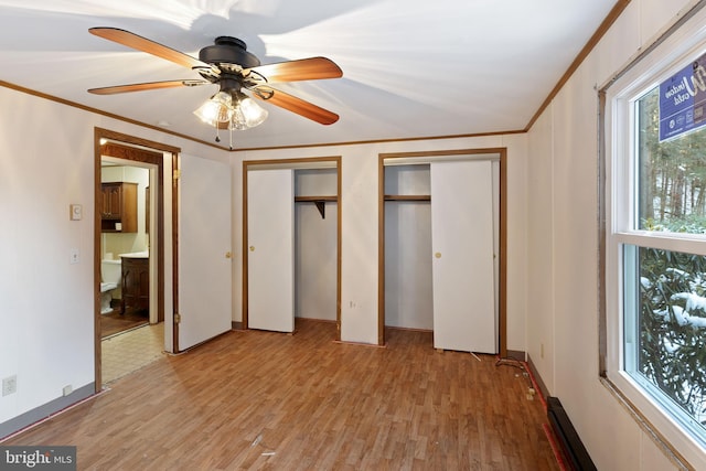 unfurnished bedroom featuring light wood-type flooring, two closets, ceiling fan, and crown molding