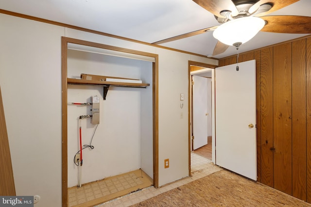 bedroom with a closet, ceiling fan, and wooden walls