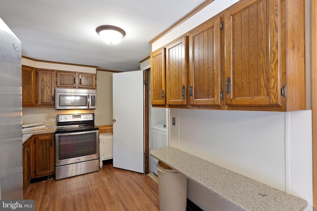 kitchen with light stone counters, stainless steel appliances, and light hardwood / wood-style floors