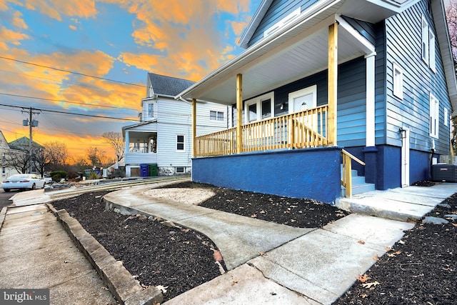 property exterior at dusk featuring cooling unit and a porch