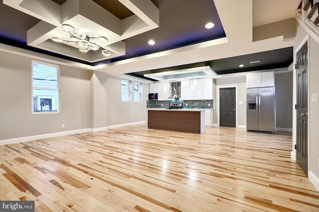 kitchen with backsplash, a raised ceiling, stainless steel refrigerator with ice dispenser, a kitchen island, and white cabinetry