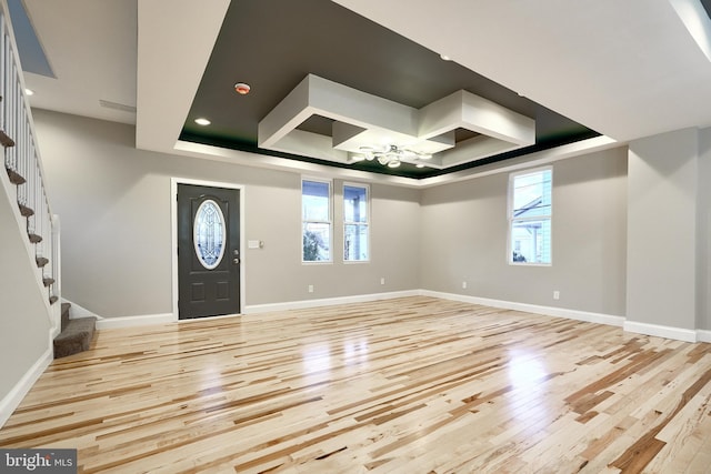 foyer with light wood-type flooring and a tray ceiling