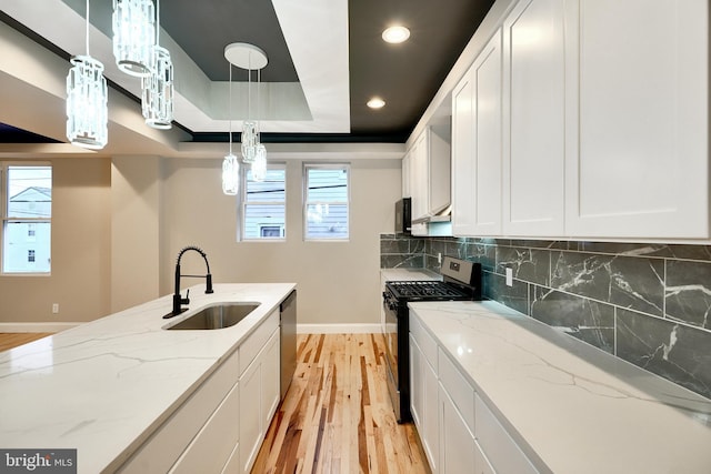 kitchen featuring white cabinetry, sink, stainless steel appliances, a raised ceiling, and tasteful backsplash