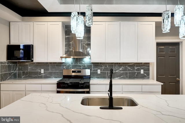 kitchen with white cabinetry, stainless steel gas stove, light stone countertops, sink, and tasteful backsplash