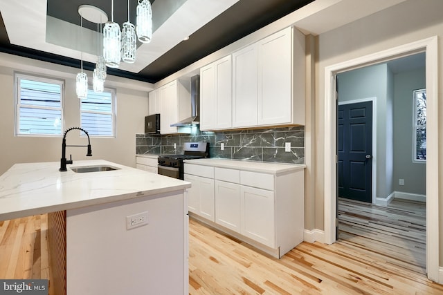 kitchen featuring gas stove, white cabinetry, sink, and a tray ceiling