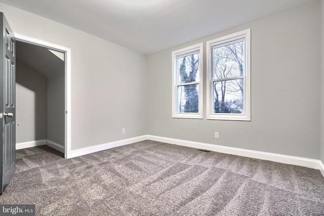 spare room featuring dark colored carpet