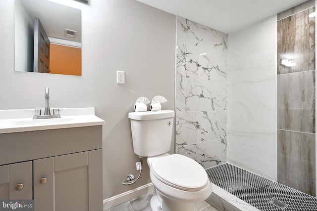 bathroom featuring tile patterned floors, toilet, a tile shower, and vanity