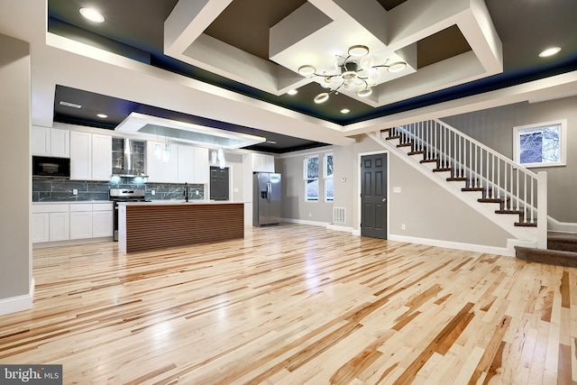 kitchen featuring stainless steel appliances, white cabinetry, a tray ceiling, and wall chimney range hood