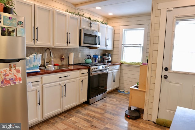 kitchen featuring sink, white cabinets, light hardwood / wood-style floors, backsplash, and appliances with stainless steel finishes