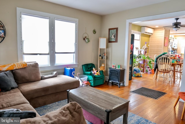 living room with ceiling fan, light hardwood / wood-style floors, and a wall mounted AC