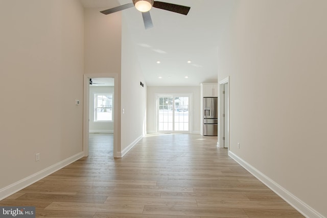 hall featuring a towering ceiling and light hardwood / wood-style flooring