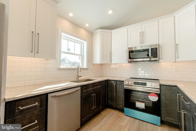 kitchen featuring backsplash, white cabinetry, light wood-type flooring, and appliances with stainless steel finishes