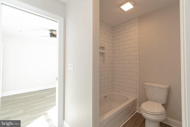 bathroom featuring tiled shower / bath combo, hardwood / wood-style flooring, and toilet