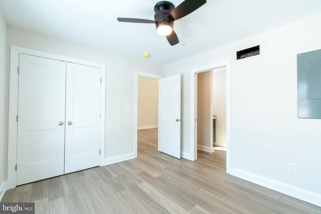 unfurnished bedroom with ceiling fan, light hardwood / wood-style floors, electric panel, and a closet