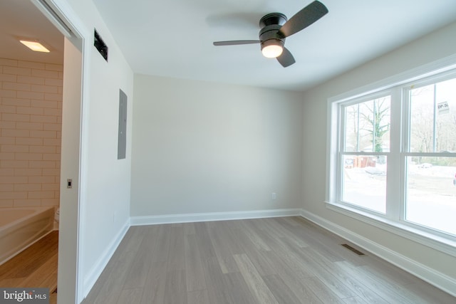 unfurnished room with ceiling fan, electric panel, and light hardwood / wood-style flooring