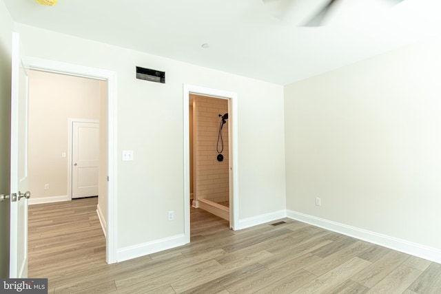 unfurnished bedroom featuring ensuite bathroom and light wood-type flooring