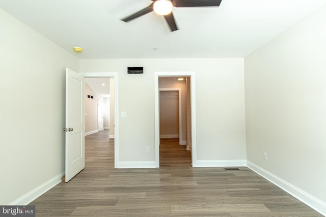 unfurnished bedroom with a spacious closet, a closet, ceiling fan, and light hardwood / wood-style floors