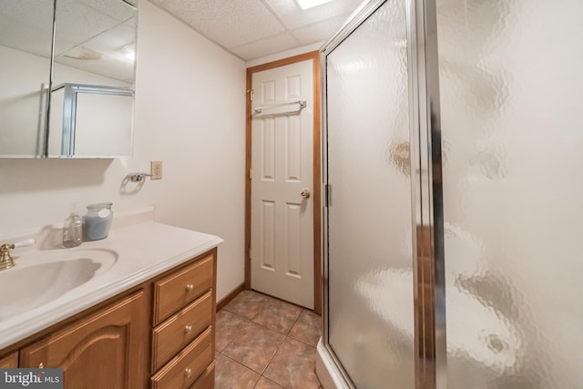 bathroom featuring an enclosed shower, vanity, a drop ceiling, and tile patterned floors