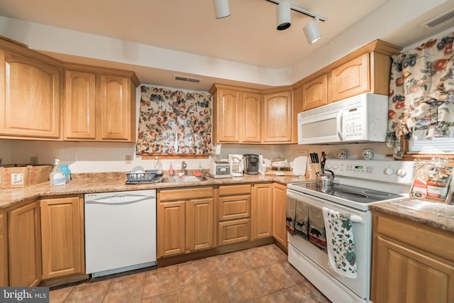 kitchen with sink, white appliances, track lighting, light tile patterned floors, and light stone counters