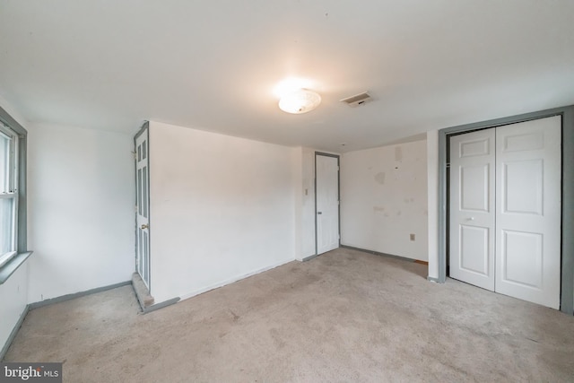 unfurnished bedroom with a closet and light colored carpet