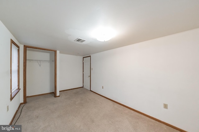 unfurnished bedroom with light colored carpet and a closet