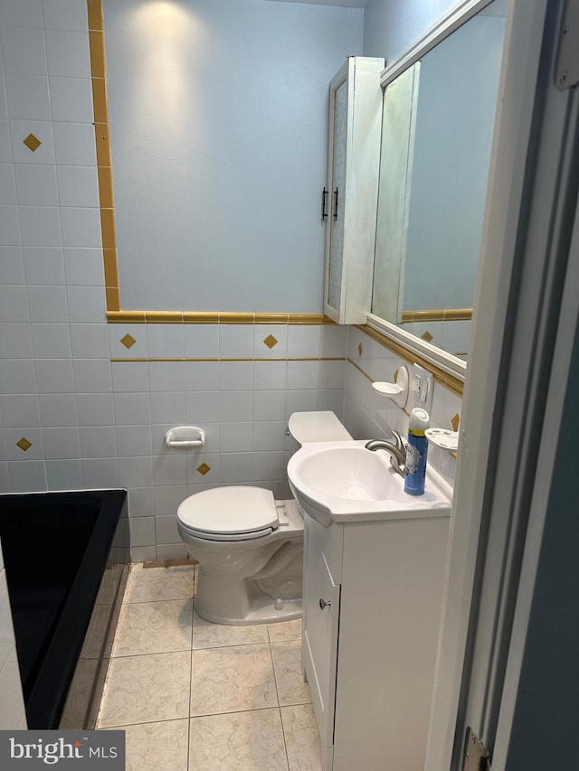 bathroom featuring tile patterned flooring, vanity, tile walls, and toilet