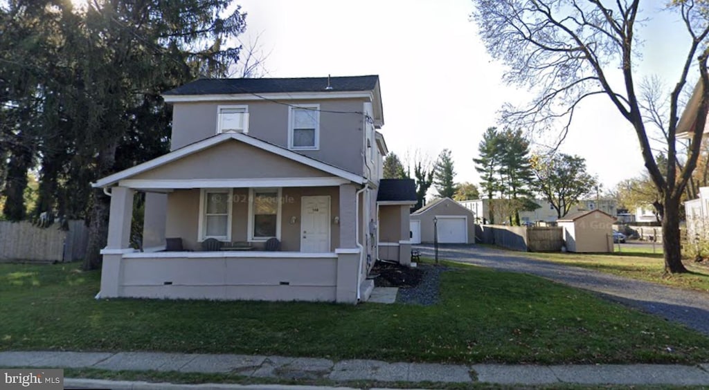 view of front of home featuring a porch, a front yard, an outdoor structure, and a garage