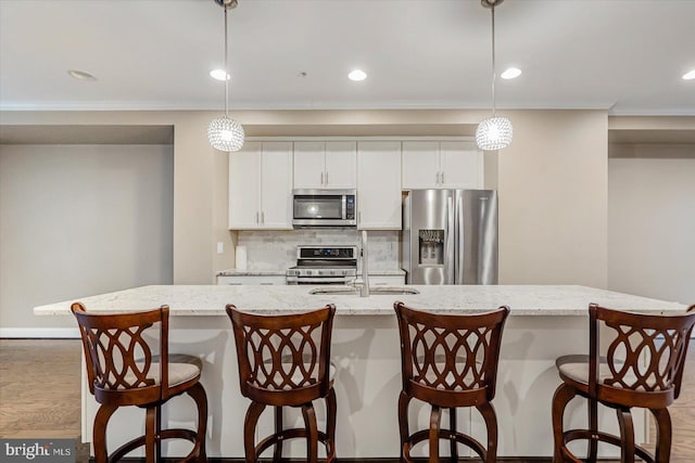 kitchen with hanging light fixtures, an island with sink, and appliances with stainless steel finishes