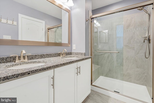 bathroom with a shower with door, vanity, and tile patterned floors