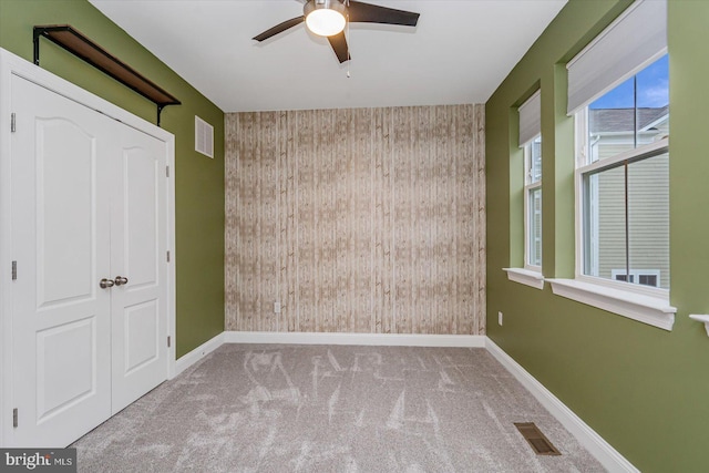 unfurnished bedroom with ceiling fan, light colored carpet, and wooden walls