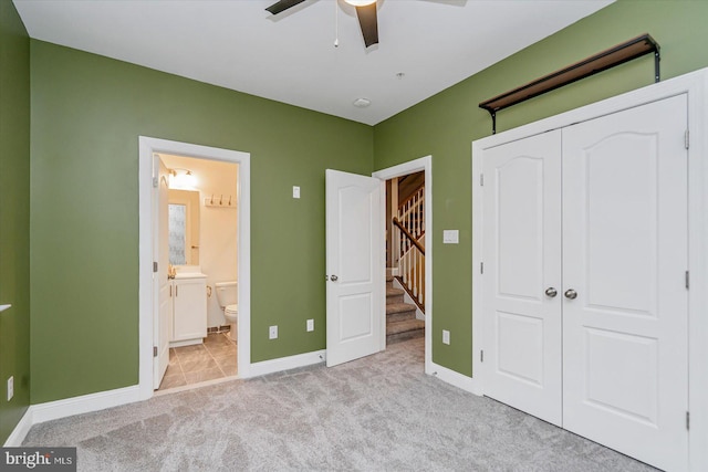 unfurnished bedroom featuring ceiling fan, light colored carpet, ensuite bath, and a closet