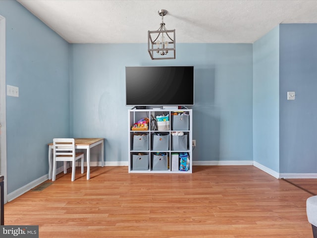 recreation room with a textured ceiling, an inviting chandelier, and hardwood / wood-style floors